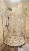 Ściana pod prysznicem wyłożona beżową mozaiką z trawertynu